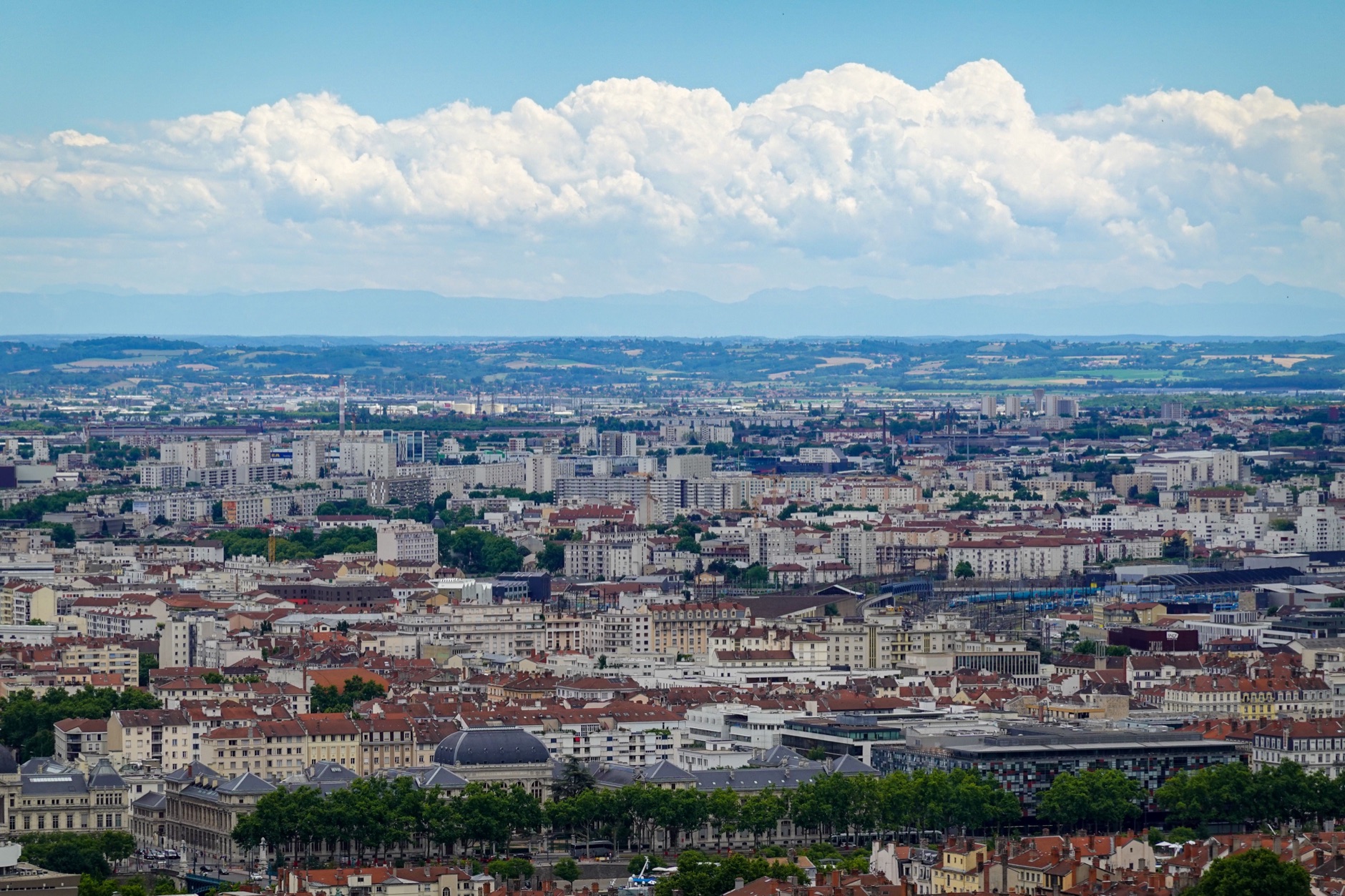 vue aérienne de la ville de Lyon avec ses toits caractéristiques et les Alpes visibles à l'horizon