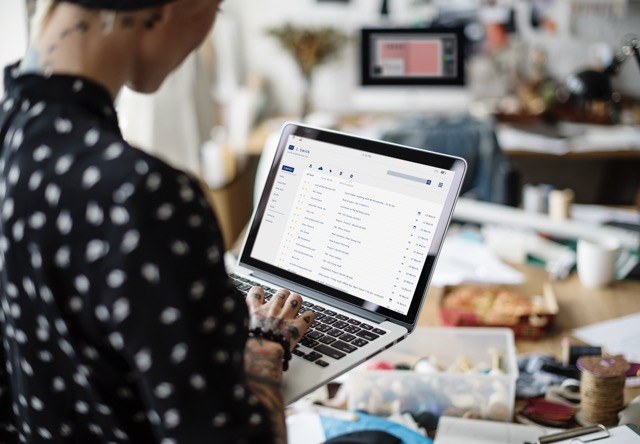 Femme tatouée consultant une boîte de réception emailing sur son ordinateur portable