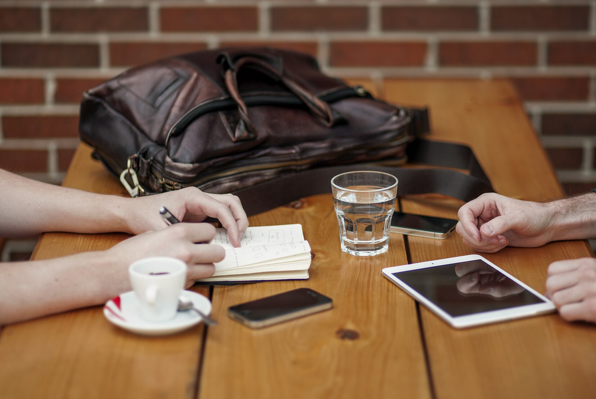 premier rendez-vous autour d'une table en bois : carnet de notes, téléphones, tablette et café