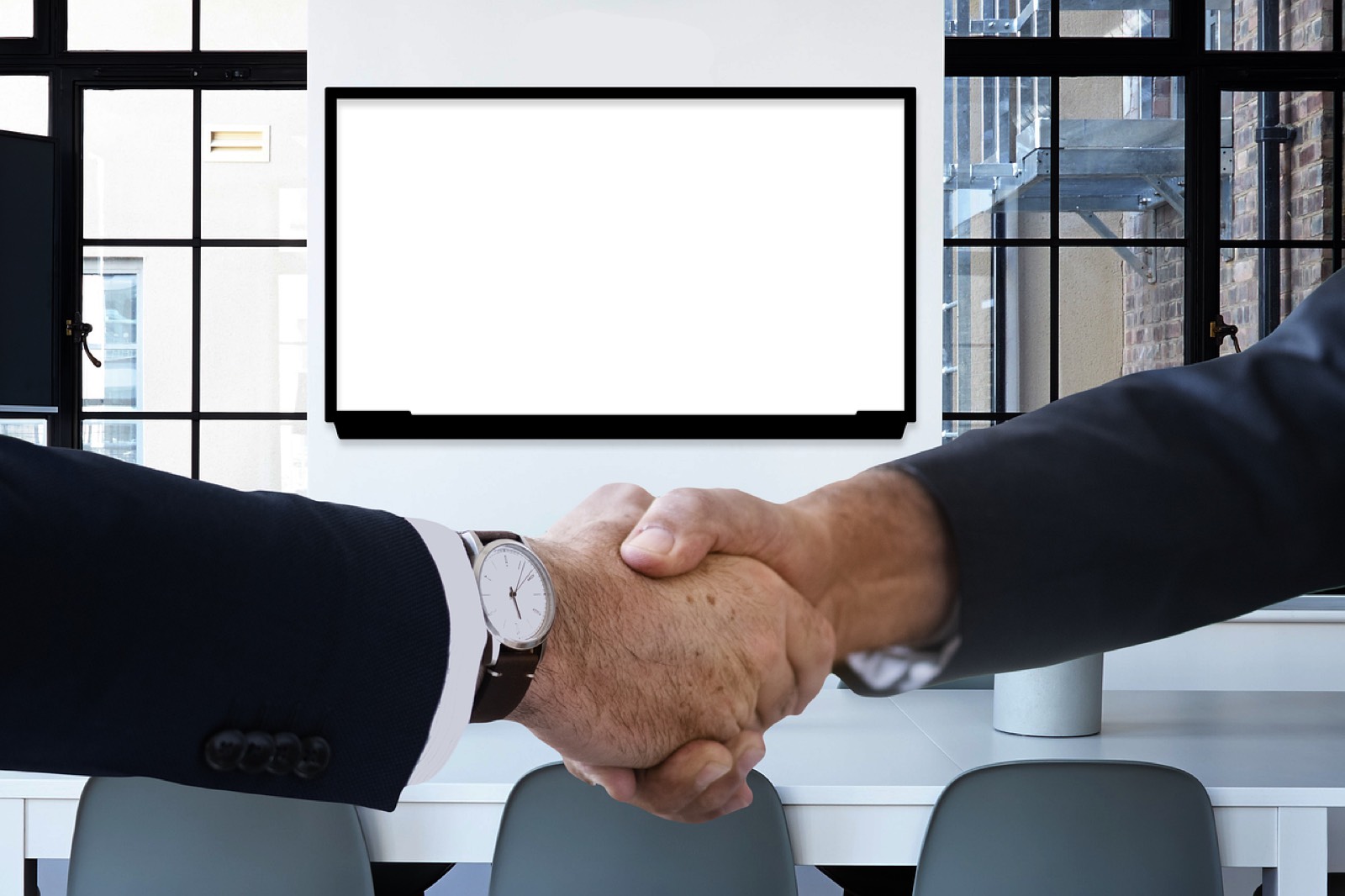 Poignée de main entre un dirigeant et un prestataire web, documents de devis sur la table